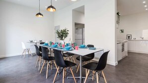 A modern dining area with a long table, black chairs with wooden legs, and pendant lighting. - Student Only The Cam Foundry (Cambridge)