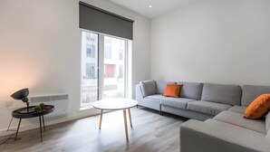 A modern living room with a grey sofa, a small round table, and a floor lamp. - Student Only The Cam Foundry (Cambridge)