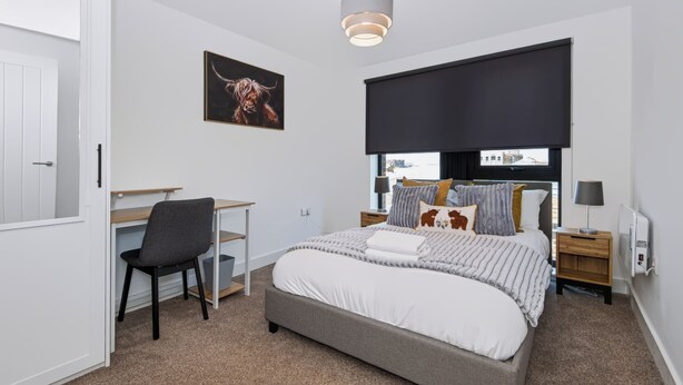A bedroom with a bed, a desk, a chair, a painting, and a window with a view. - Cozy Liverpool City Center 2BDR Stay (Liverpool)