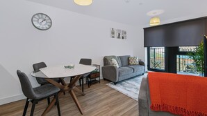 A modern living room with a round dining table, grey sofa, and a red throw blanket. - Cozy Liverpool City Center 2BDR Stay (Liverpool)