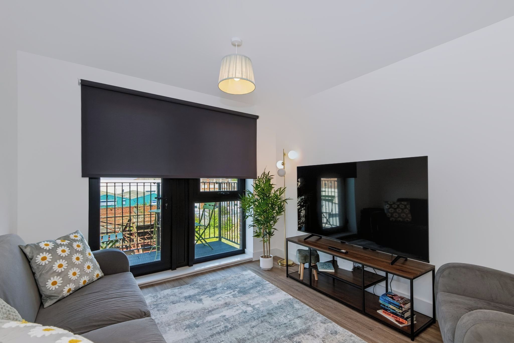 A modern living room with a large flat-screen TV, a sofa, a coffee table, and a potted plant.