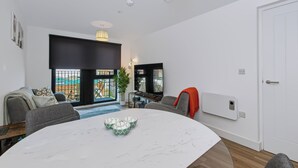 A modern living room with a dining table, sofa, and a large window. - Cozy Liverpool City Center 2BDR Stay (Liverpool)