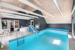Ein Hallenbad mit Rutsche, Whirlpool und Sitzgelegenheit.