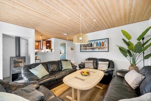 Ein modernes Wohnzimmer mit Kamin, Ledersofas, einem Couchtisch und einer großen Pflanze.