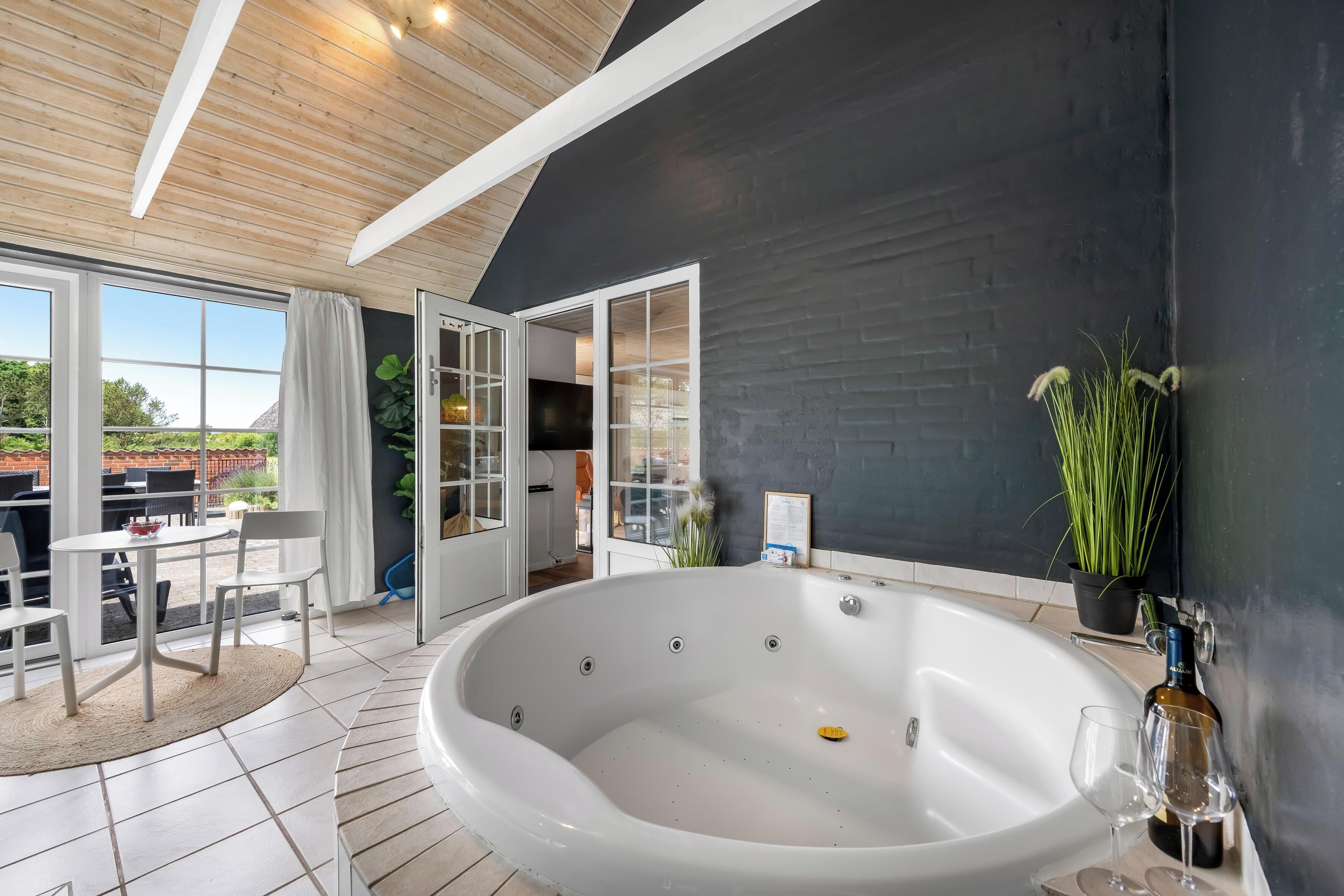 Een moderne badkamer met een groot bad, een douchecabine van glas en een potplant.