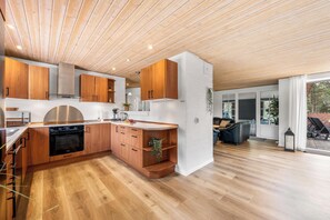 A modern kitchen with wooden cabinets, a built-in oven, and a large window.
