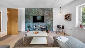 Ein modernes Wohnzimmer mit Flachbildfernseher, Holztür und Bücherregal.