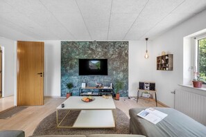 Ein modernes Wohnzimmer mit Flachbildfernseher, Holztür und Bücherregal.