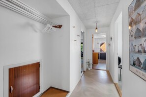 A hallway with a wooden door, white walls, a ceiling with a textured finish, and a framed picture on the right wall.