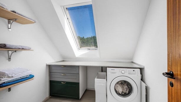Ein kleiner Hauswirtschaftsraum mit Oberlicht, Waschmaschine und Regalen für Stauraum.