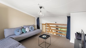 A modern room with a sofa, a small table, a TV, and a balcony with wooden railings. - Lovely holiday apartment in the heart of Søndervig close to the North Sea (Ringkøbing)