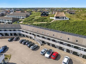 Ein Parkplatz mit mehreren Autos und einem Gebäude im modernen Stil.