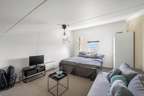 Ein Schlafzimmer mit einem Bett, einem Fernseher, einem kleinen Tisch und einem Fenster.