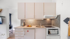 A modern kitchen with white cabinets, a built-in oven, and a countertop with a kettle and vegetables. - Lovely holiday apartment in the heart of Søndervig close to the North Sea (Ringkøbing)