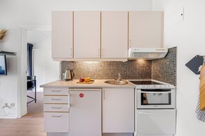 Eine moderne Küche mit weißen Schränken, einem eingebauten Backofen und einer Arbeitsplatte mit Wasserkocher und Gemüse.