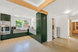 A modern kitchen with built-in appliances, a large window, and a view of greenery outside. - Modernized ground floor holiday apartment in Stadil (Tim)