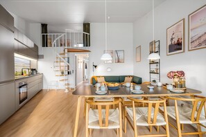 Una cucina moderna con zona pranzo, sedie in legno, una scala e vista sull'esterno.