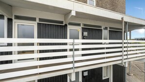 A building with a white balcony railing, multiple windows, and a door with a sign. - Bright and newly renovated holiday apartment close to the North Sea and. (Ringkøbing)