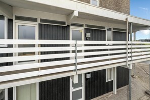 A building with a white balcony railing, multiple windows, and a door with a sign. - Bright and newly renovated holiday apartment close to the North Sea and. (Ringkøbing)