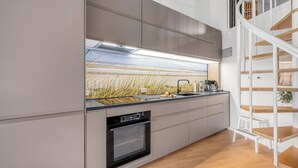 A modern kitchen with a built-in oven, a sink, and a staircase leading to an upper level. - Bright and newly renovated holiday apartment close to the North Sea and. (Ringkøbing)