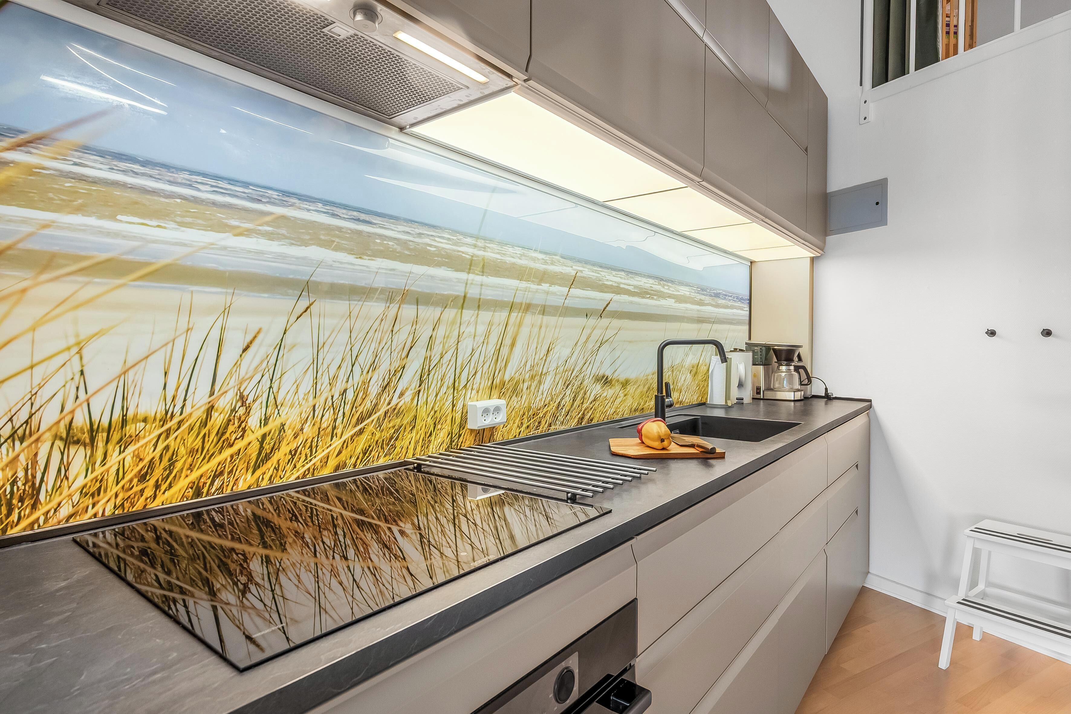 A kitchen with a large window, a sink, and a countertop.