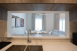 A modern kitchen with a built-in dining area, a stainless steel sink, and a dining table with chairs. - Bloomfields 2Br in Fairways 3 (Abu Dhabi)