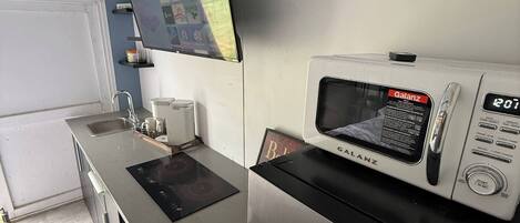 Une cuisine moderne équipée d’un four à micro-ondes encastré, d’un écran numérique et d’un réfrigérateur en acier inoxydable.