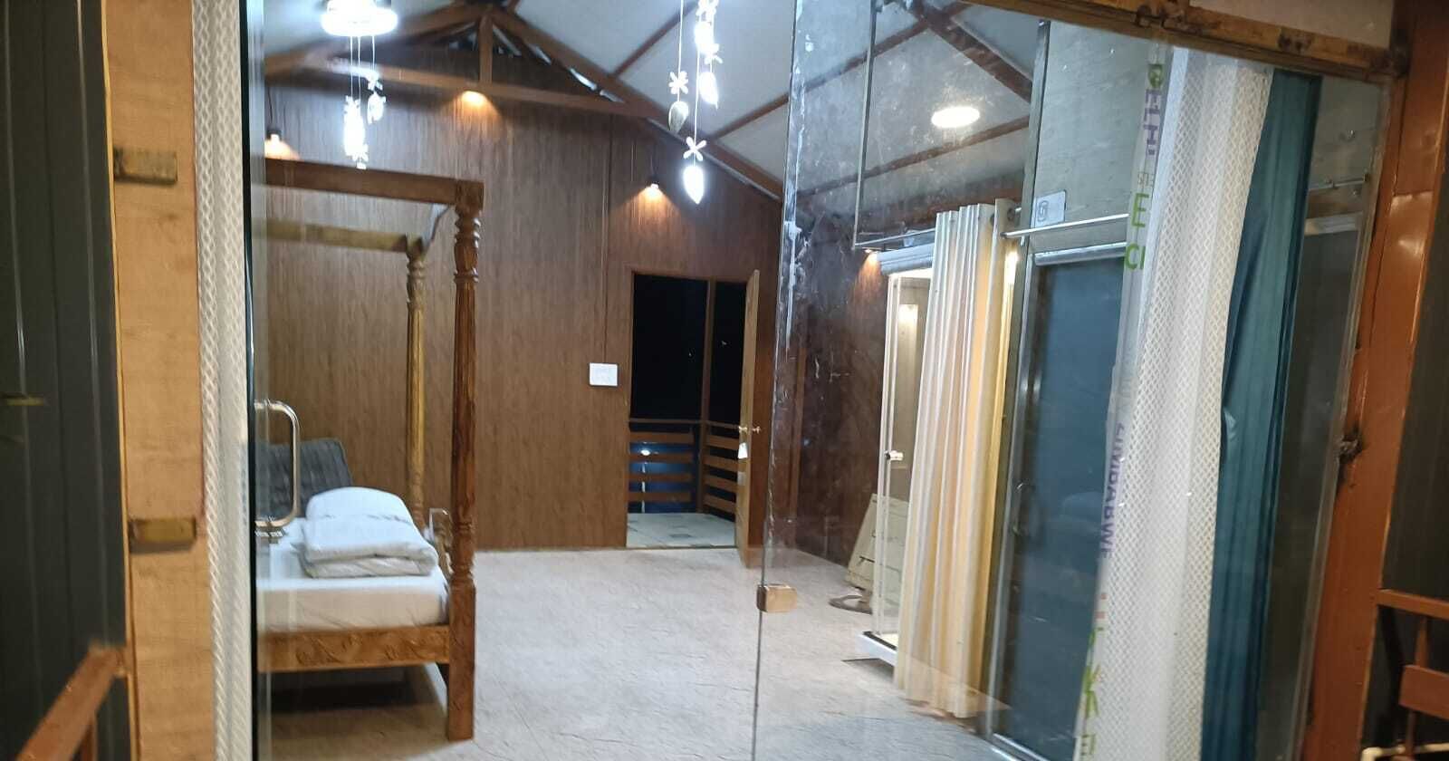 A room with a bed, a wooden chair, a glass partition, and a door.