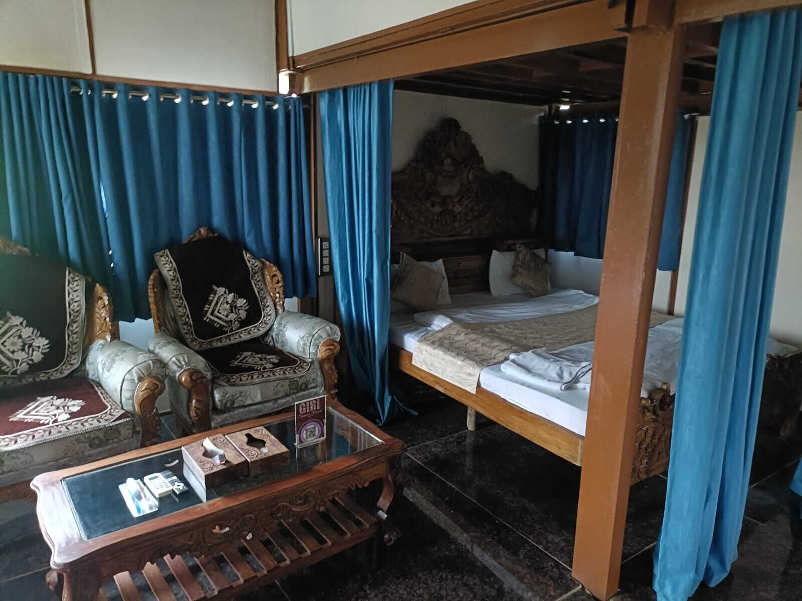 A room with a bed, a chair, a table, and curtains.