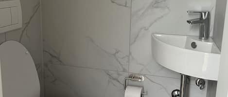 A bathroom with a toilet, a sink, and a marble-patterned wall.