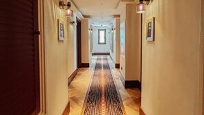 Un pasillo de hotel con alfombra estampada, luces empotradas en la pared y cuadros enmarcados.