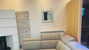 A modern living room with a sectional sofa, a fireplace, and a mirror on the wall. - Villa 'Ennio' with Private Pool, Wi-Fi and Air Conditioning (Ciampino)