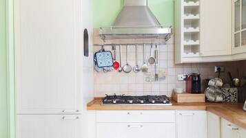 Une cuisine avec des meubles blancs, une cuisinière à gaz et une hotte en acier inoxydable.