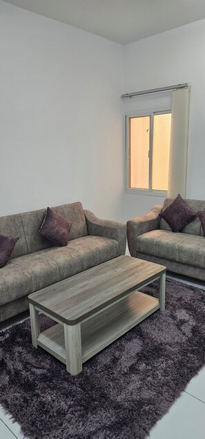 Una sala de estar moderna con dos sofás, una mesita de centro y un ventanal con cortinas.
