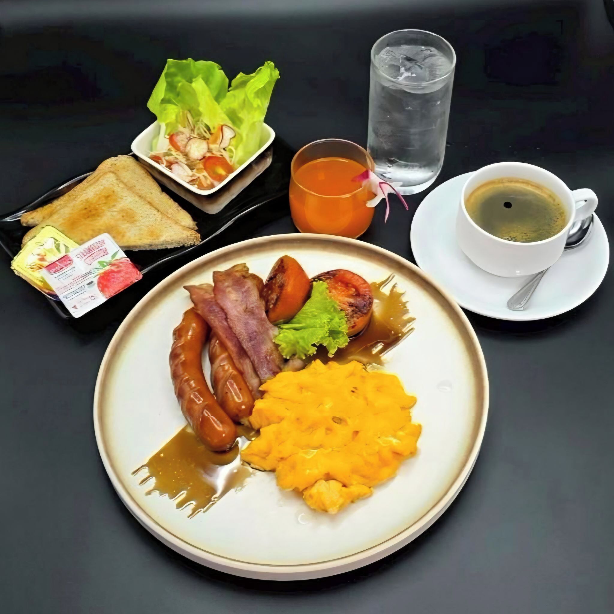 Un plato de desayuno con salchichas, tocino y puré de papas.