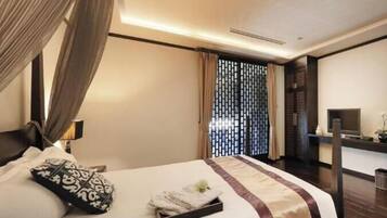 A hotel room with a bed, curtains, a desk, and a TV.