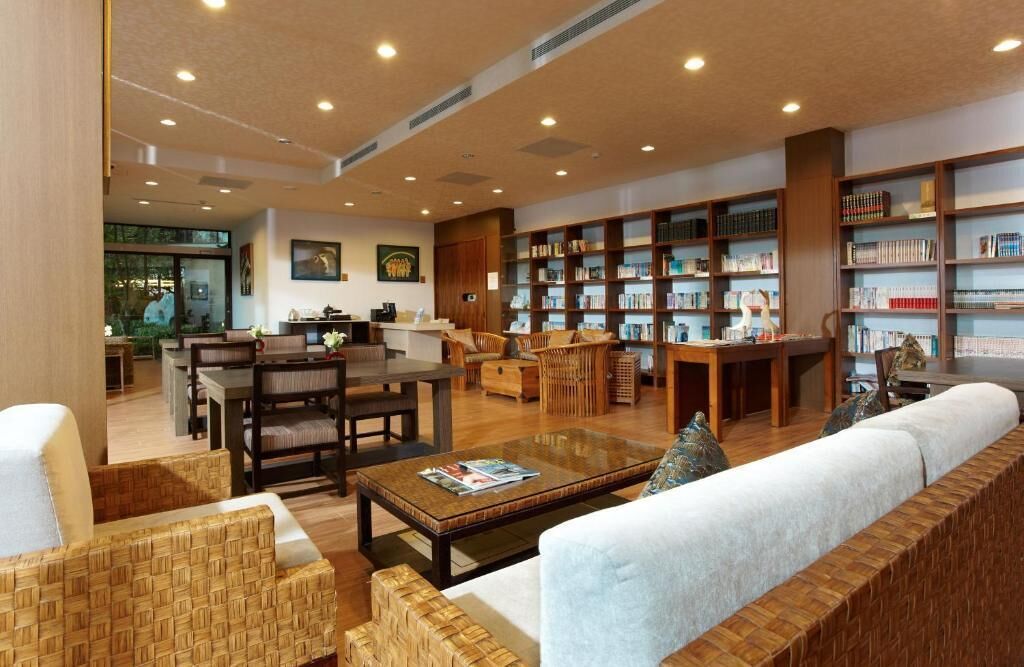 A spacious library with multiple seating areas, bookshelves, and a dining table.