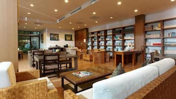 A spacious library with multiple seating areas, bookshelves, and a dining table.