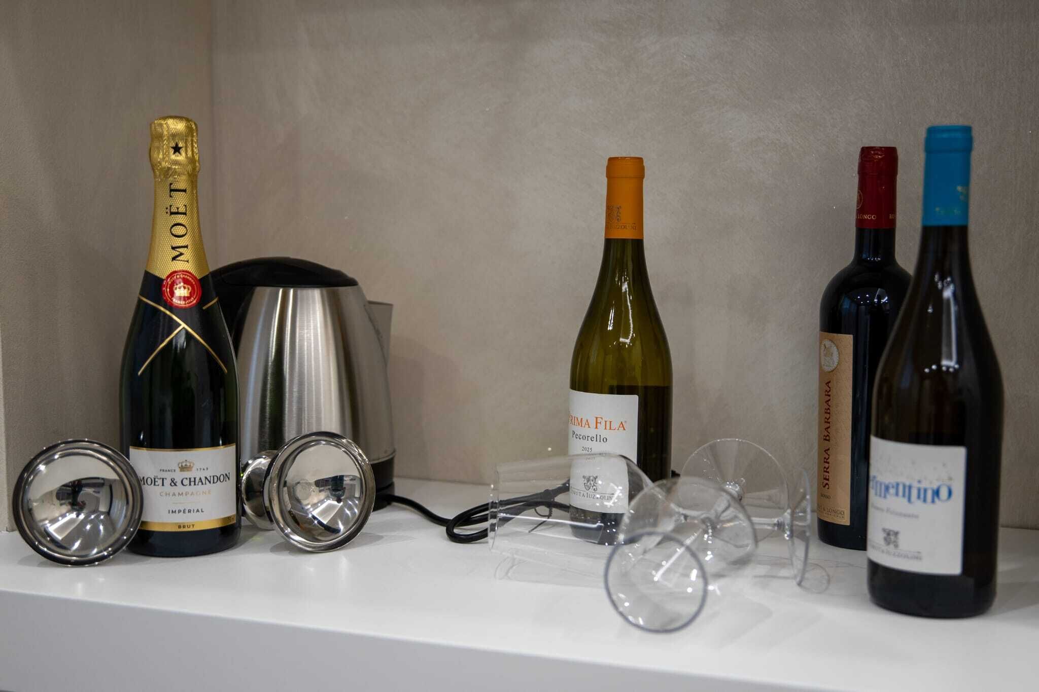 A selection of wine bottles and wine glasses on a shelf.