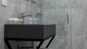 Deluxe driepersoonskamer | Badkamer | Een douche, een haardroger, handdoeken, zeep
