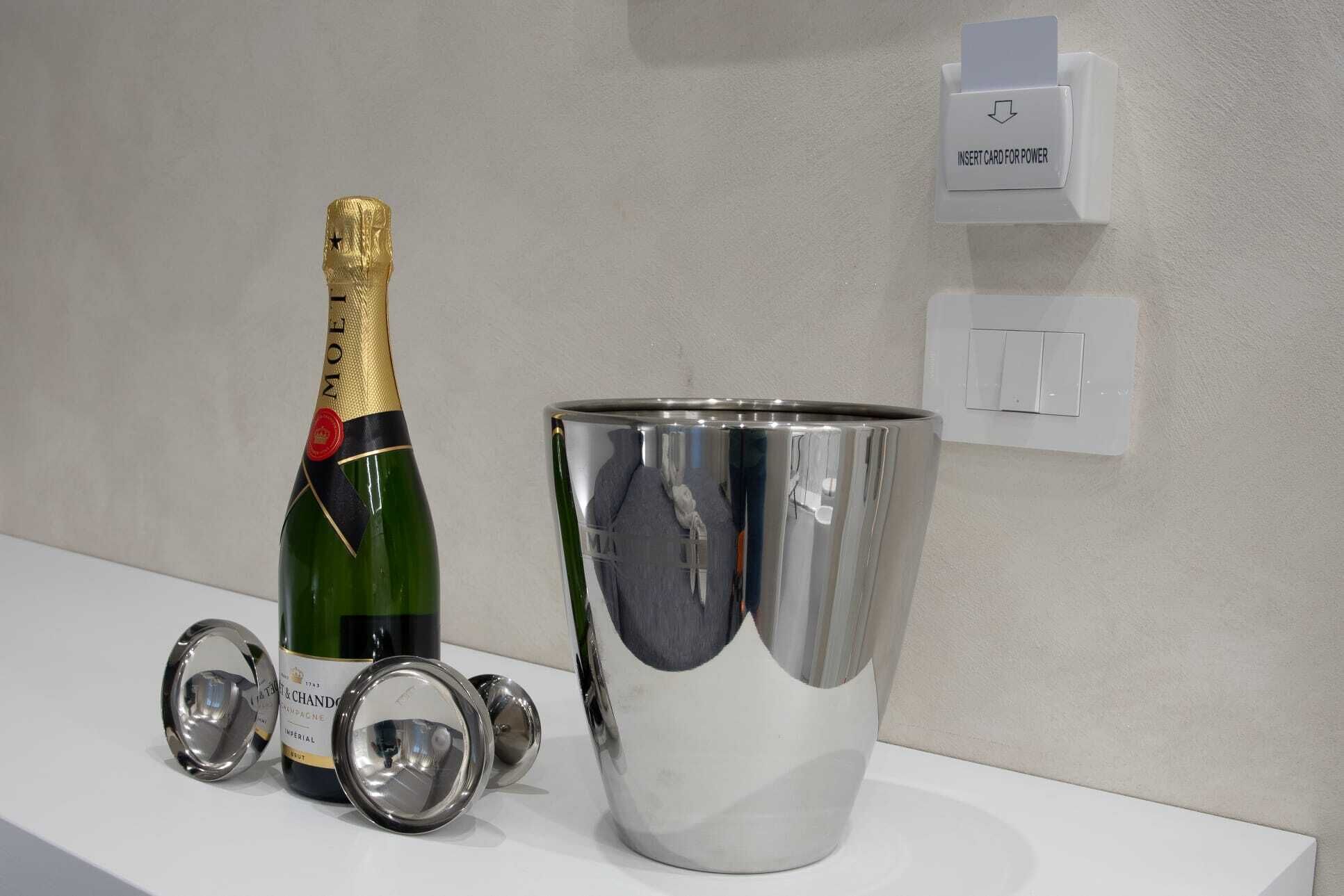 A bottle of champagne, a metallic bucket, and a wall-mounted card reader.