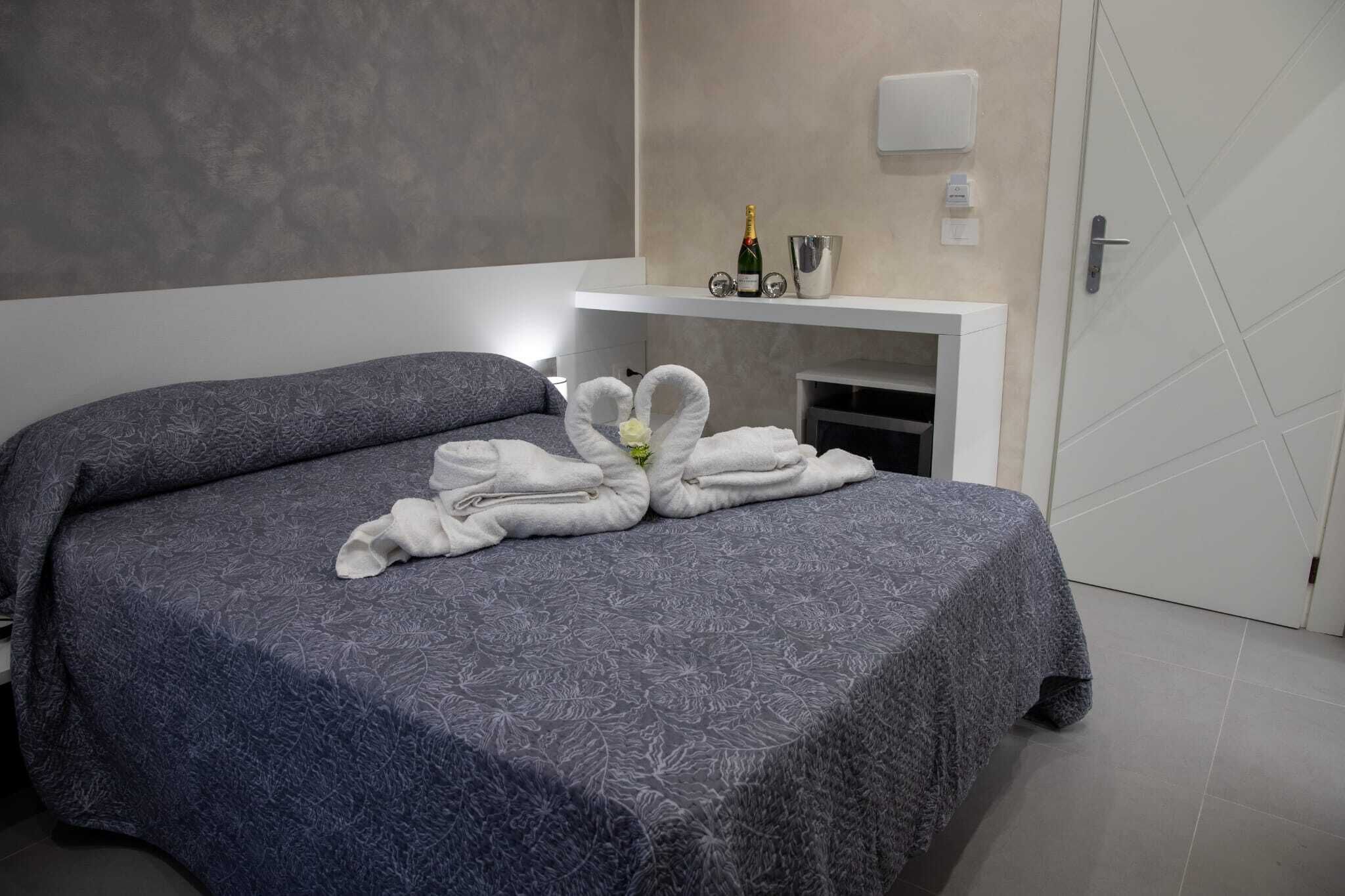 Een hotelkamer met een bed, een minibar en een deur.