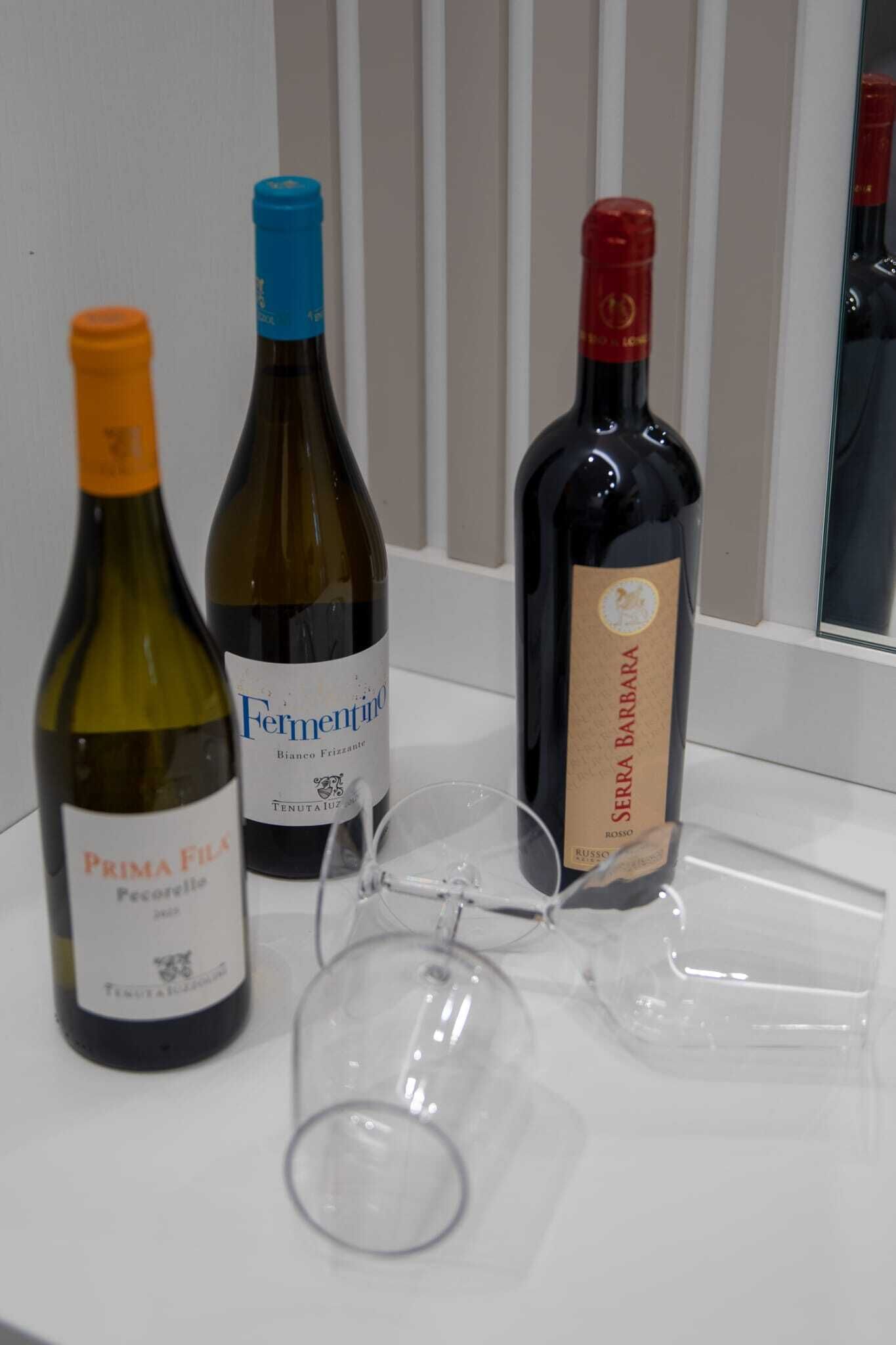 Three wine bottles and two wine glasses on a white surface.