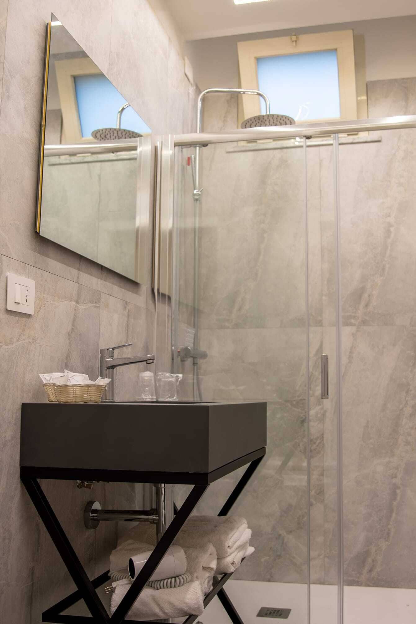 Un baño moderno con ducha envuelta en vidrio, tocador negro y espejo.
