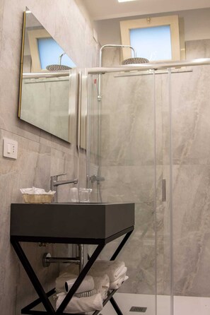 A modern bathroom with a glass-enclosed shower, a black vanity, and a mirror. - Fortuna degli Dei (Tropea)