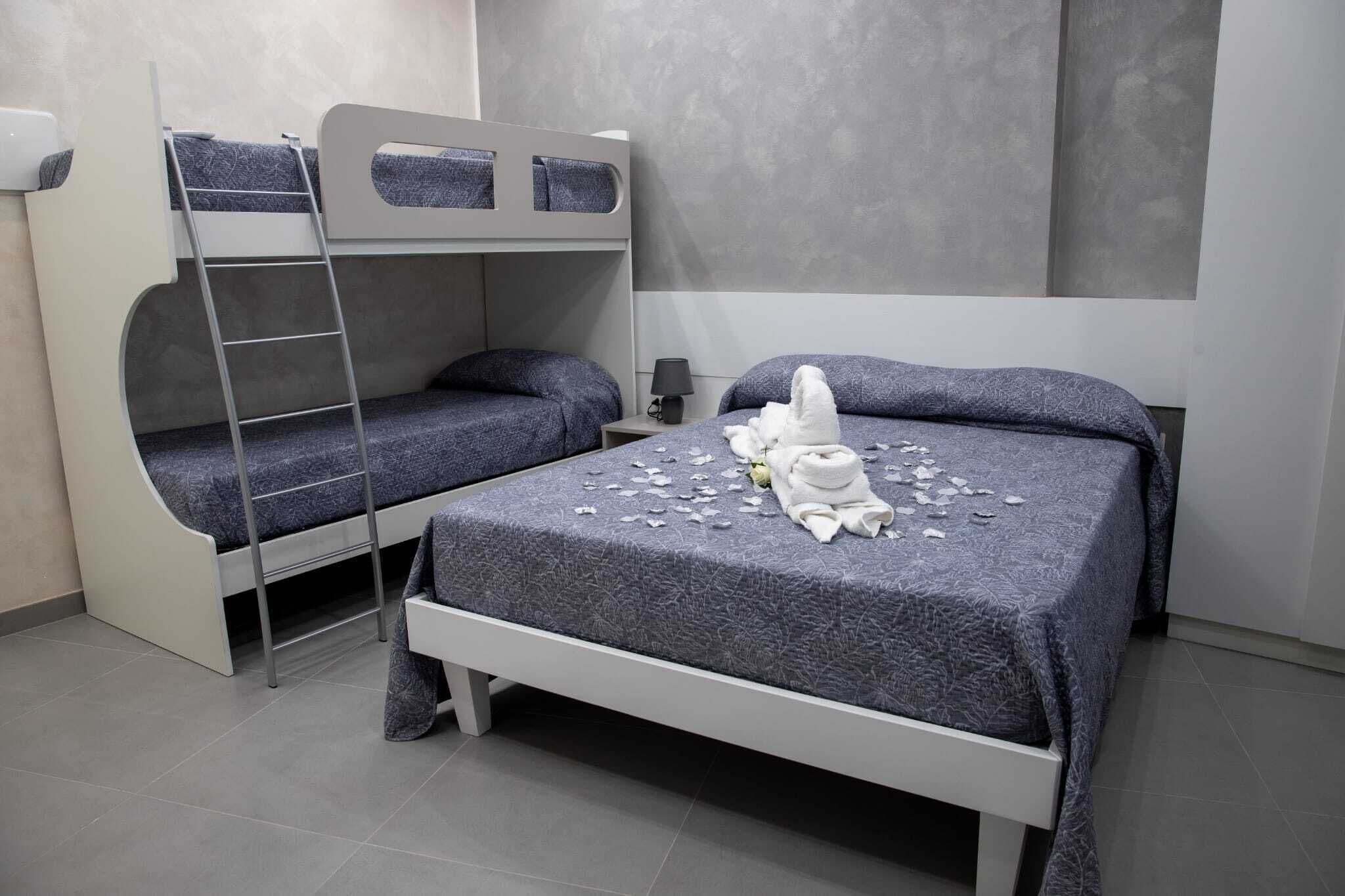 A bunk bed room with a ladder, a bedside table with a lamp, and a towel on the bed.