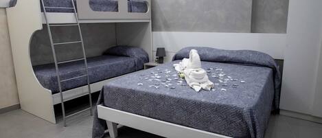 A bunk bed room with a ladder, a bedside table with a lamp, and a towel on the bed.