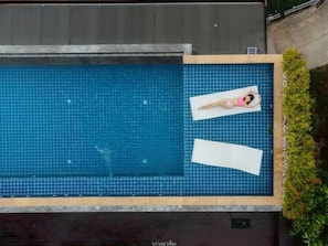 An aerial view of a swimming pool with a person lying on a lounge chair. - Sangthong Resort (Chiang Klang)