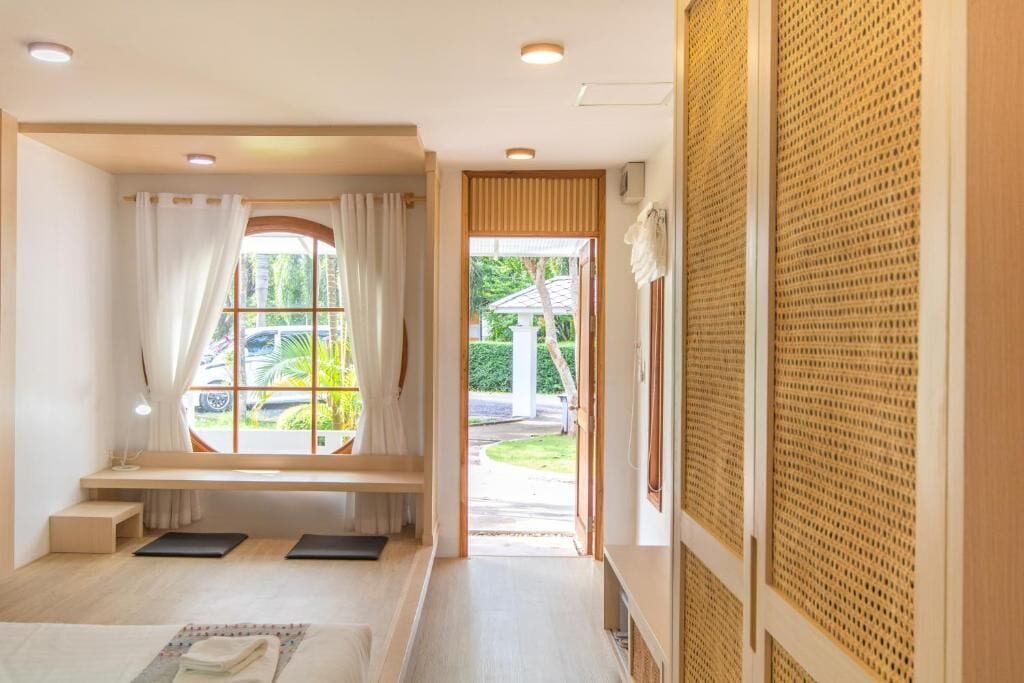 A room with a large window, a bench, and a view of the outside.