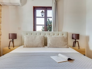 A bedroom with a bed, two bedside lamps, a window with curtains, and a wall-mounted air conditioner. - Sea-view Retreat - Villas With Pools and Private Jacuzzi Cabin (Peristerona)